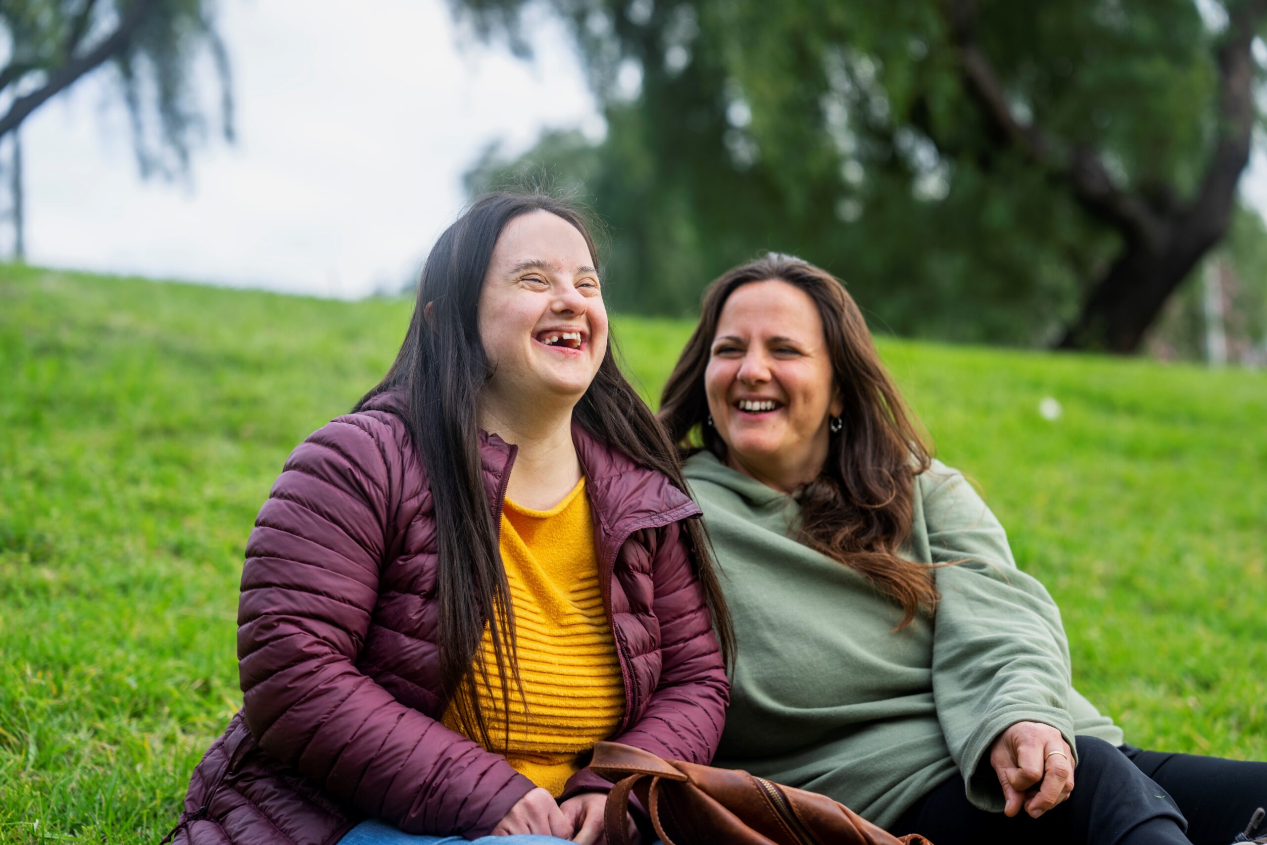 A child with a disability and her mother outside on a hill.