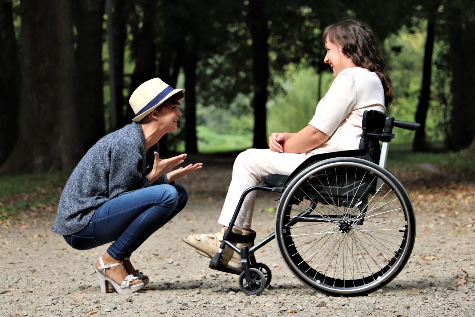 A caregiver kneeling to speak face-to-face with a person in a wheelchair.