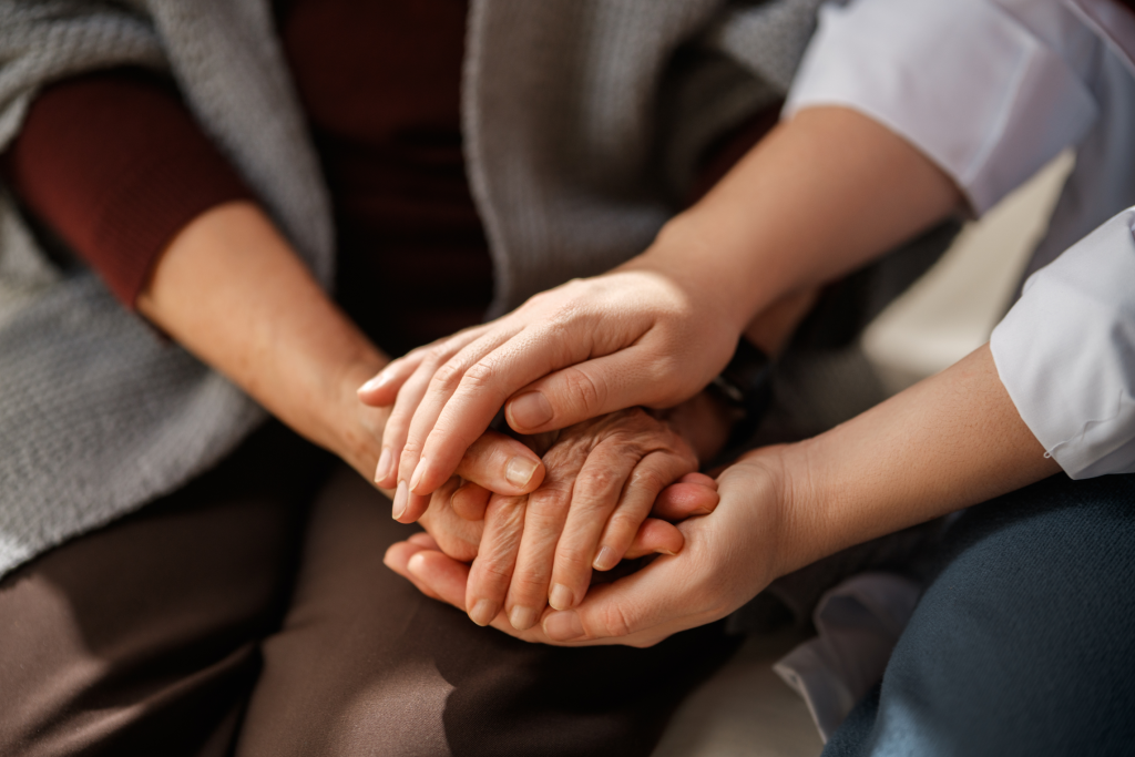 A caregiver holding the hands of an older adult.
