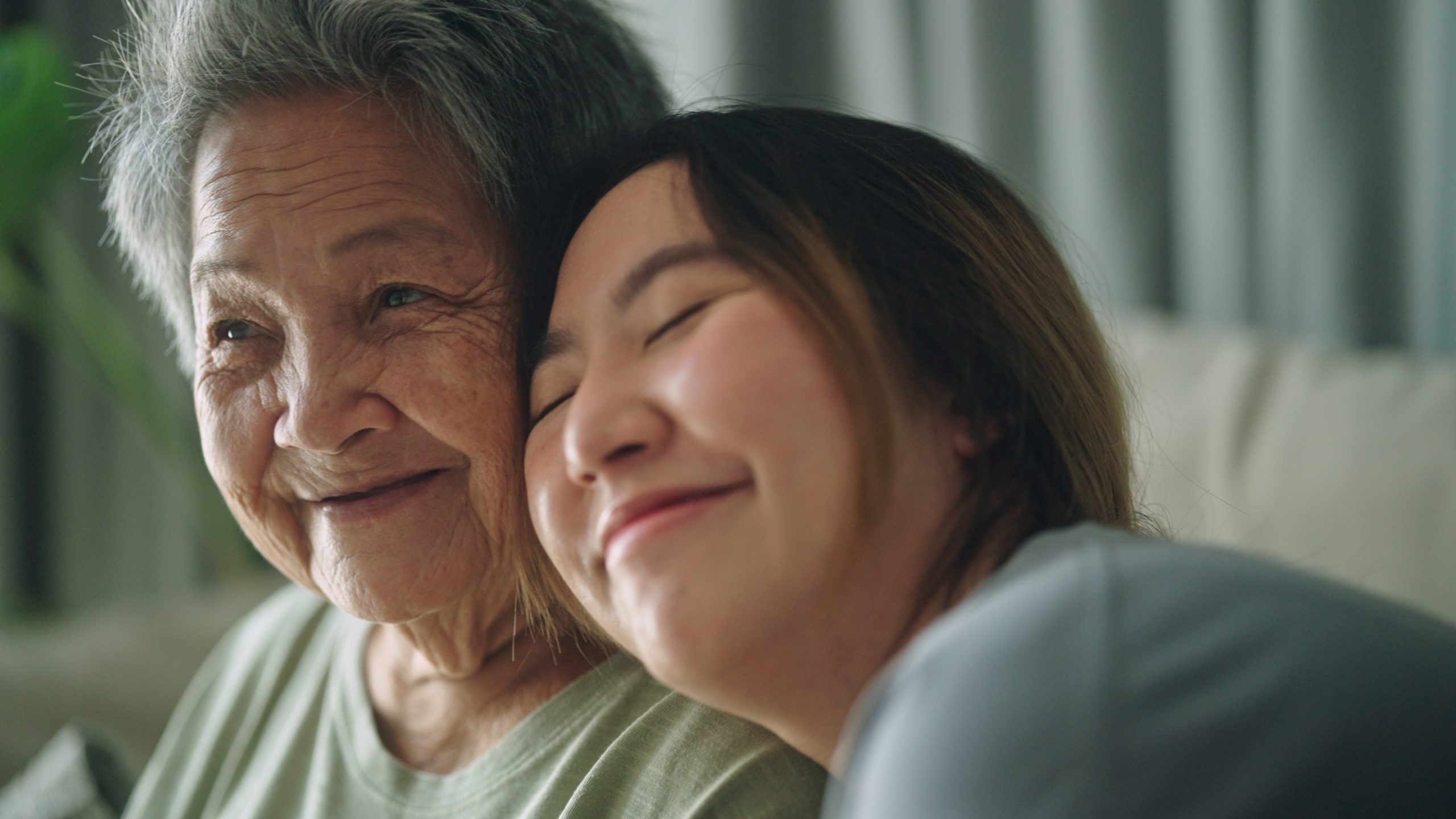 Grandmother and teenage granddaughter relax on sofa together.