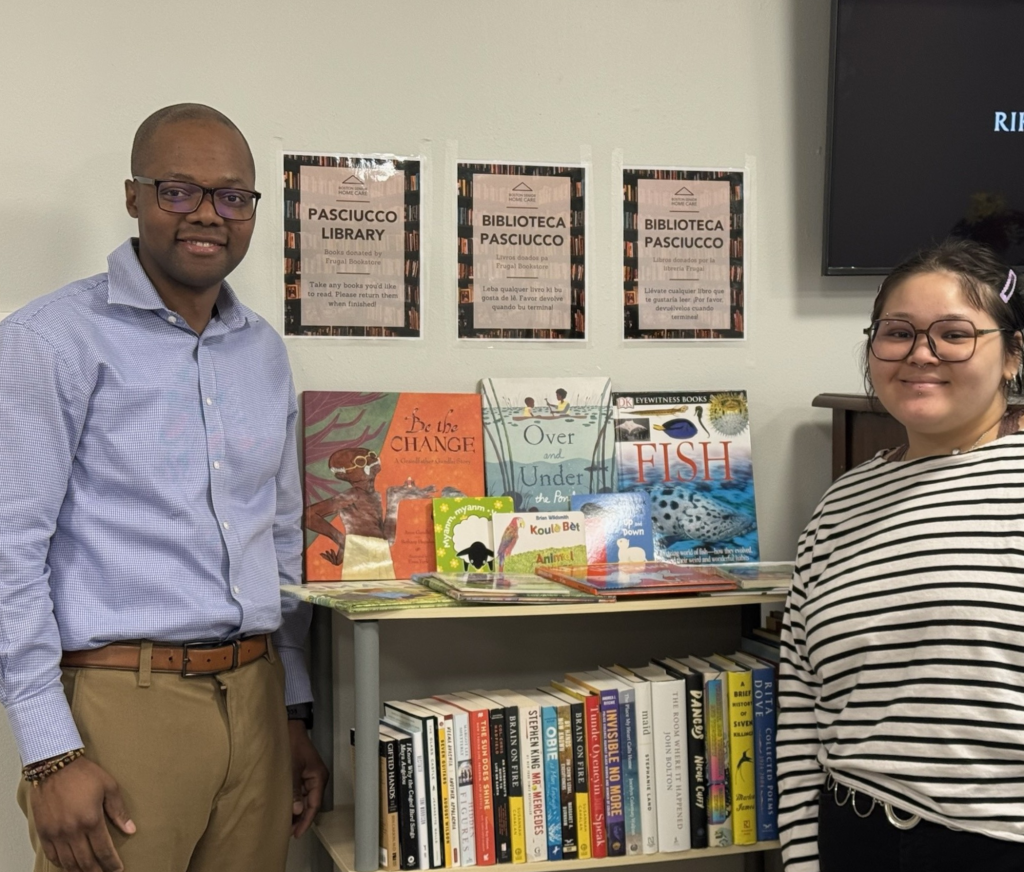 Lesses Cardoso, Tenant Resource Counselor, and Emilee Cordova, Boston Senior Home Care Intern, beside the new Pasciucco Apartments Library